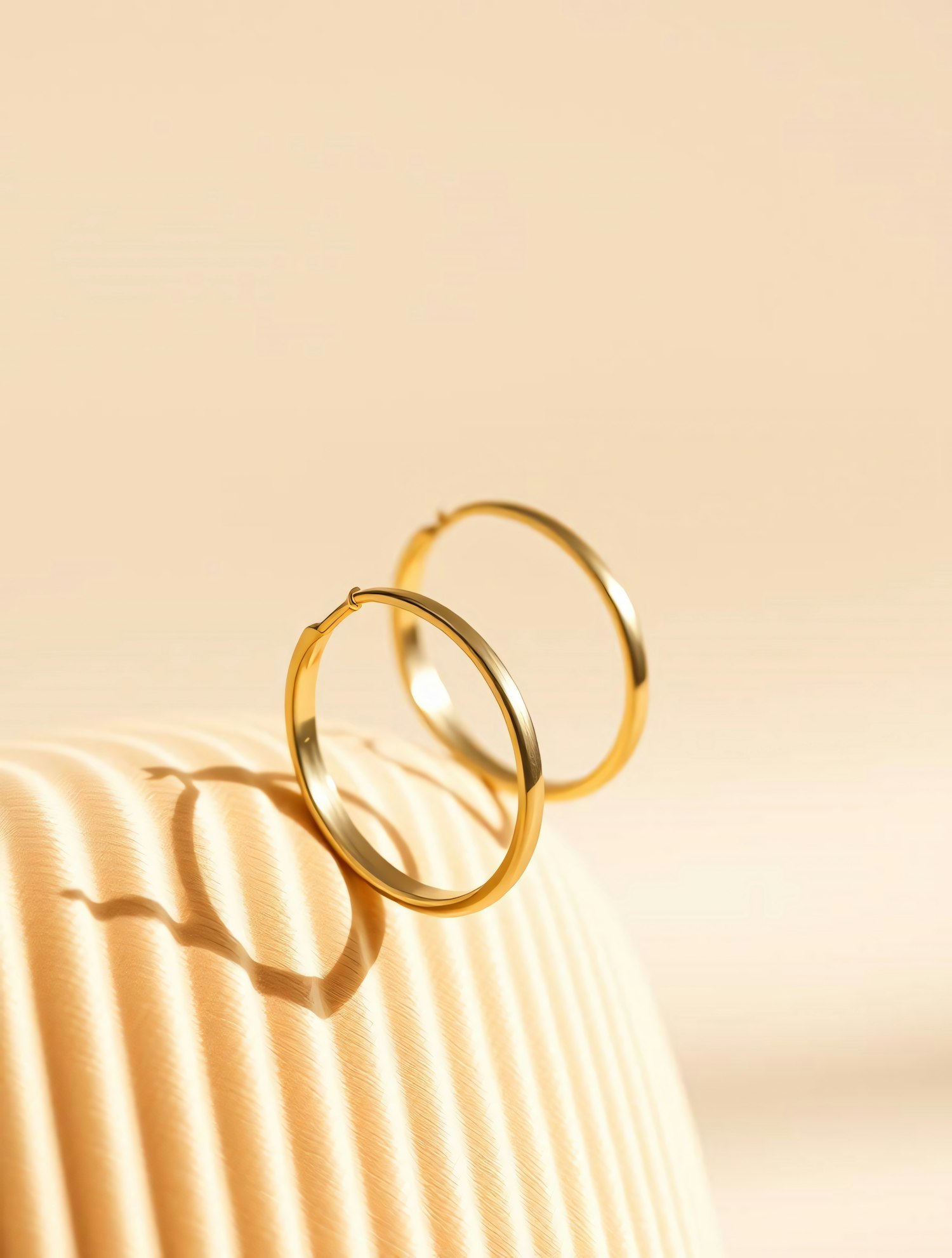 Gold Hoop Earrings on Beige Background