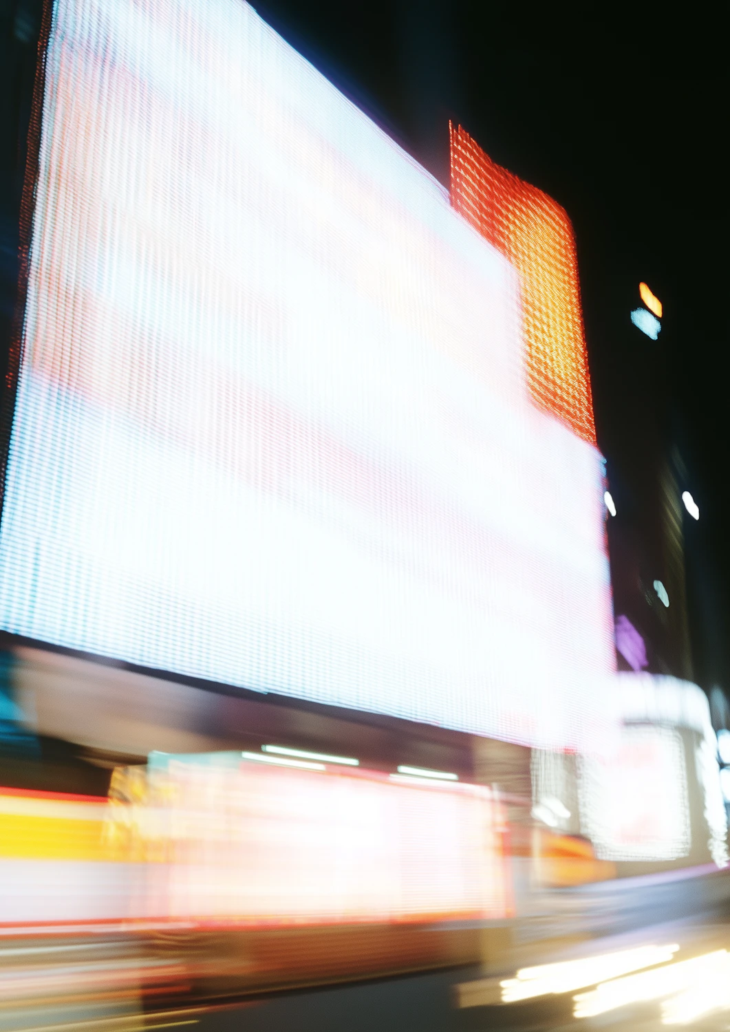 A blurred cityscape with vibrant billboards and streaking lights