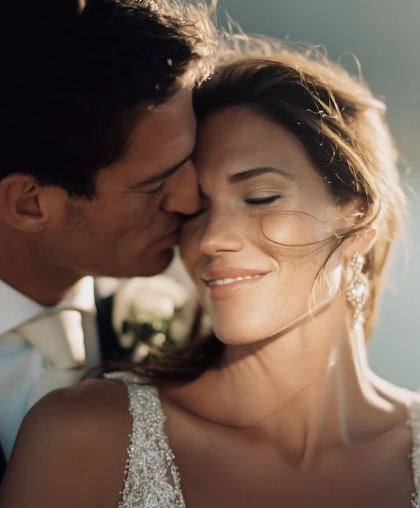 Romantic groom kiss on bride’s cheek in golden light