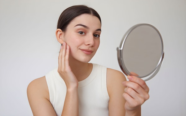 Young Woman Examining Face in Mirror