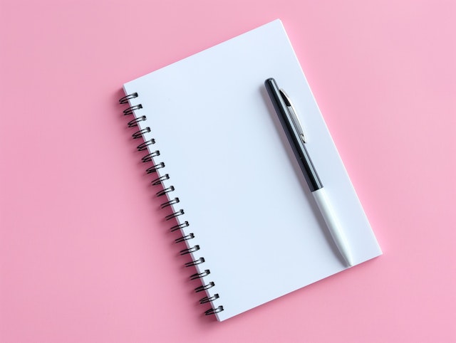 Spiral Notebook and Pen on Pink Background