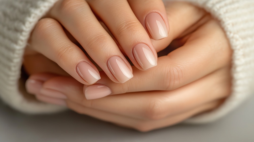 Glossy nude manicure, hands cradled