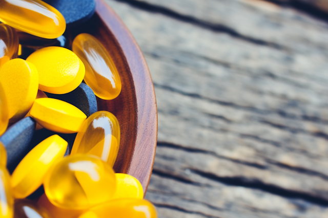 Omega-3 and Vitamin Supplement Capsules in Wooden Bowl Focus