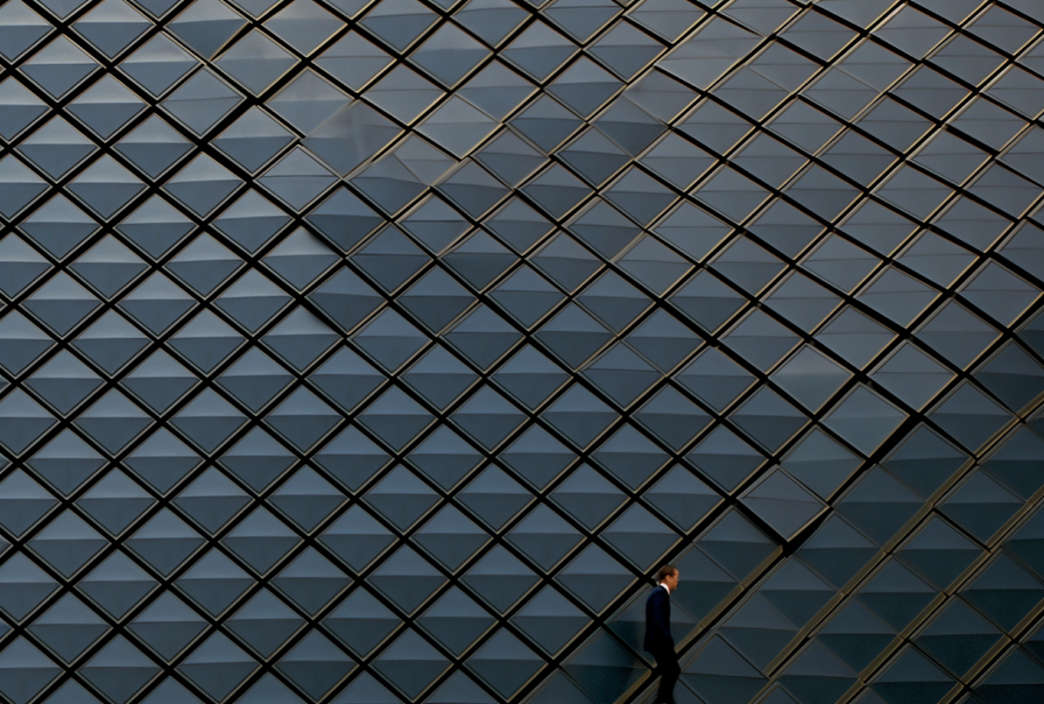 Man in Suit Walking by Geometric Patterned Wall