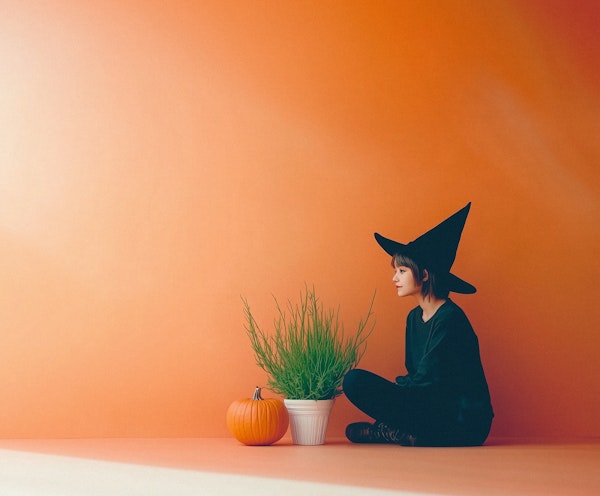 Person in Witch Hat with Pumpkin and Plant