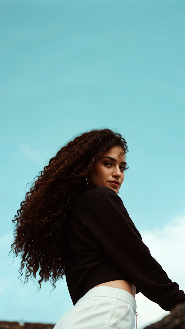 Woman with Curly Hair Against Blue Sky