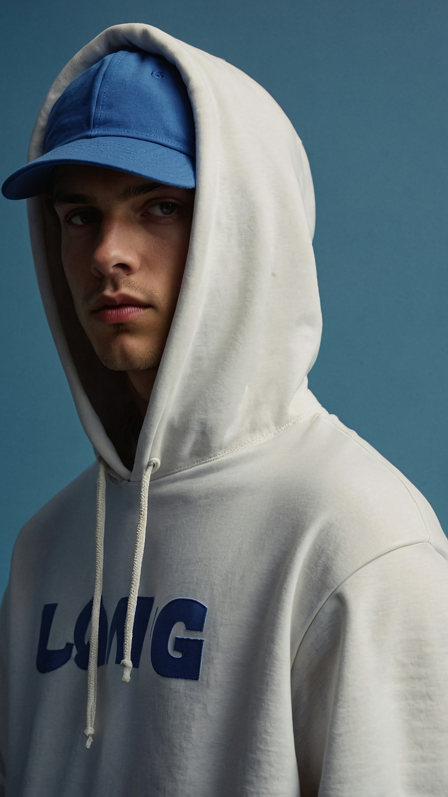 Young Man in White Hoodie and Blue Cap