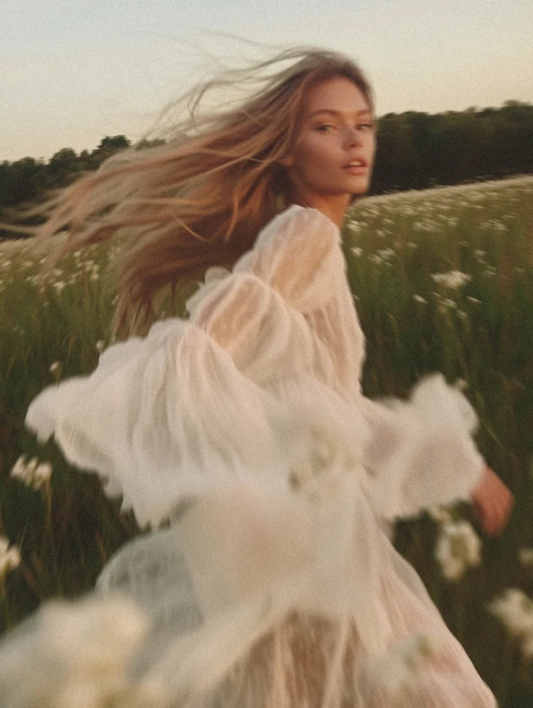 Woman in Flowing White Dress in Wildflower Field