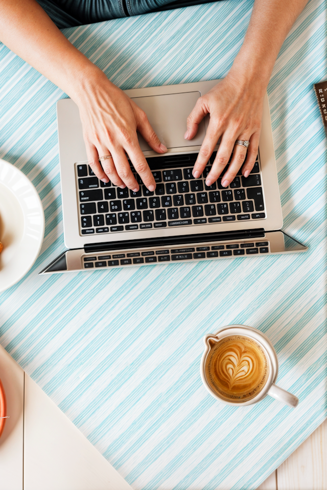 Hands Typing on Laptop with Coffee