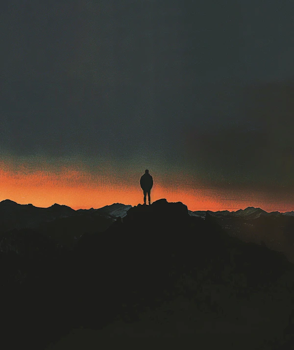 Contemplative Silhouette on Mountain Peak at Twilight