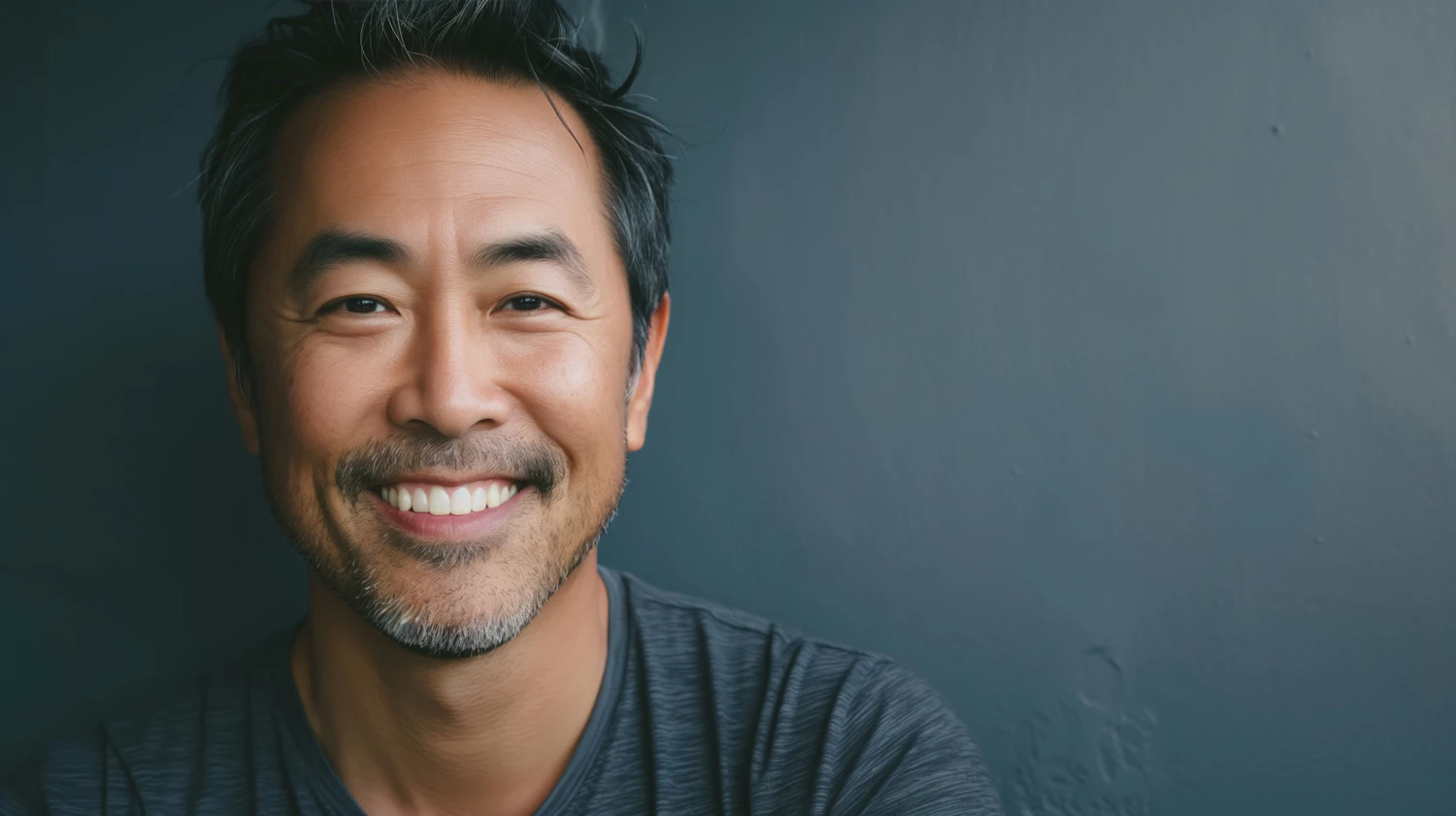 Smiling middle-aged Asian man with short dark hair and a trimmed beard