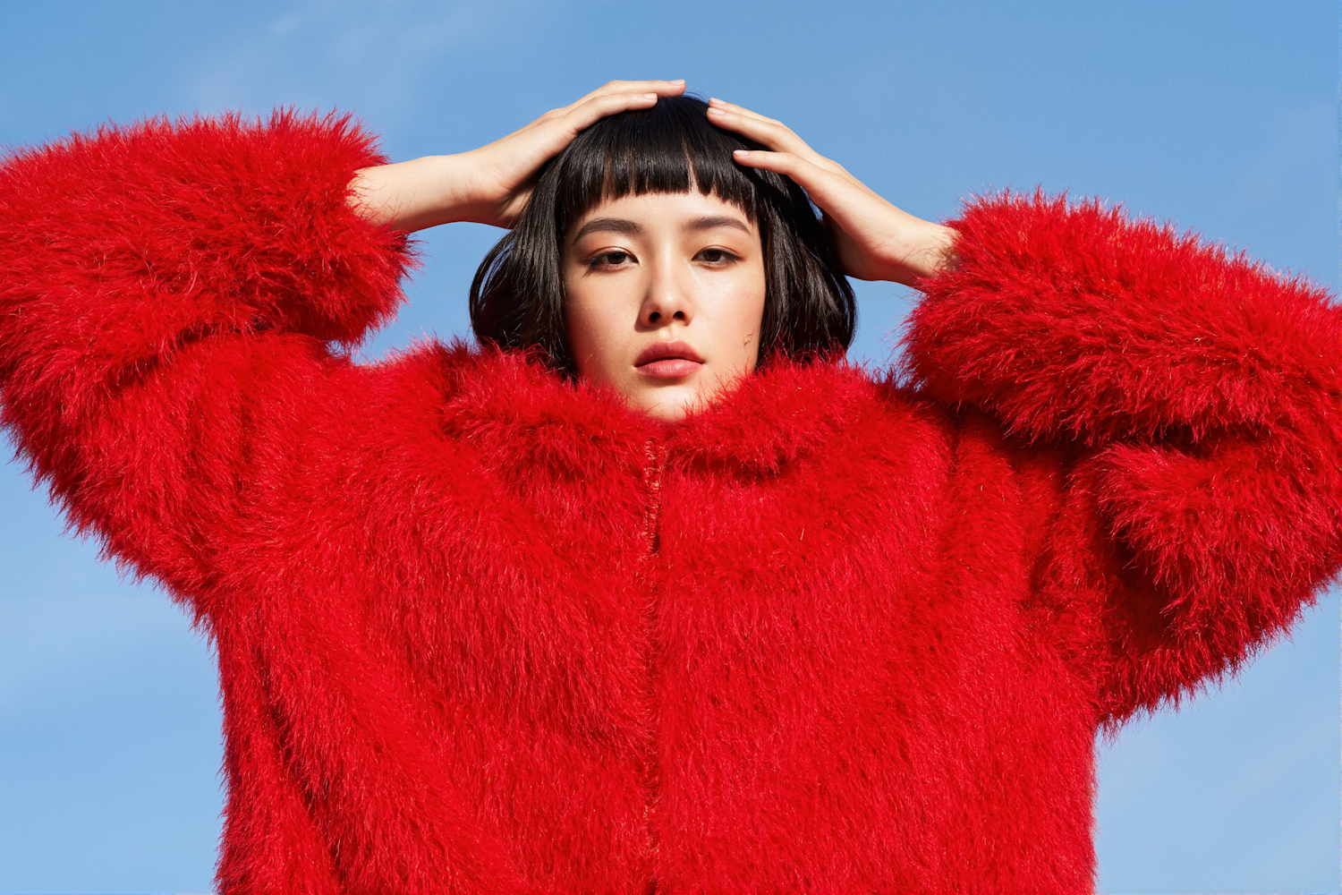 Person in Red Coat Against Blue Sky