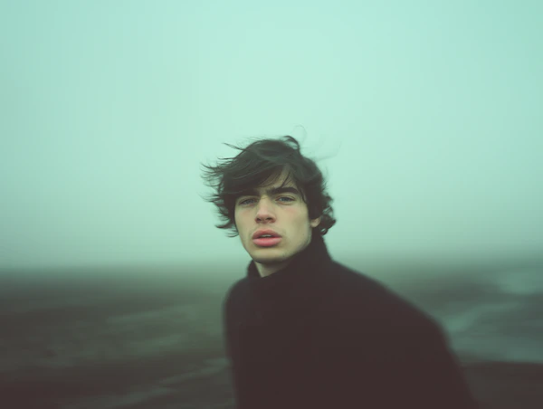 Contemplative Young Man in Misty Landscape