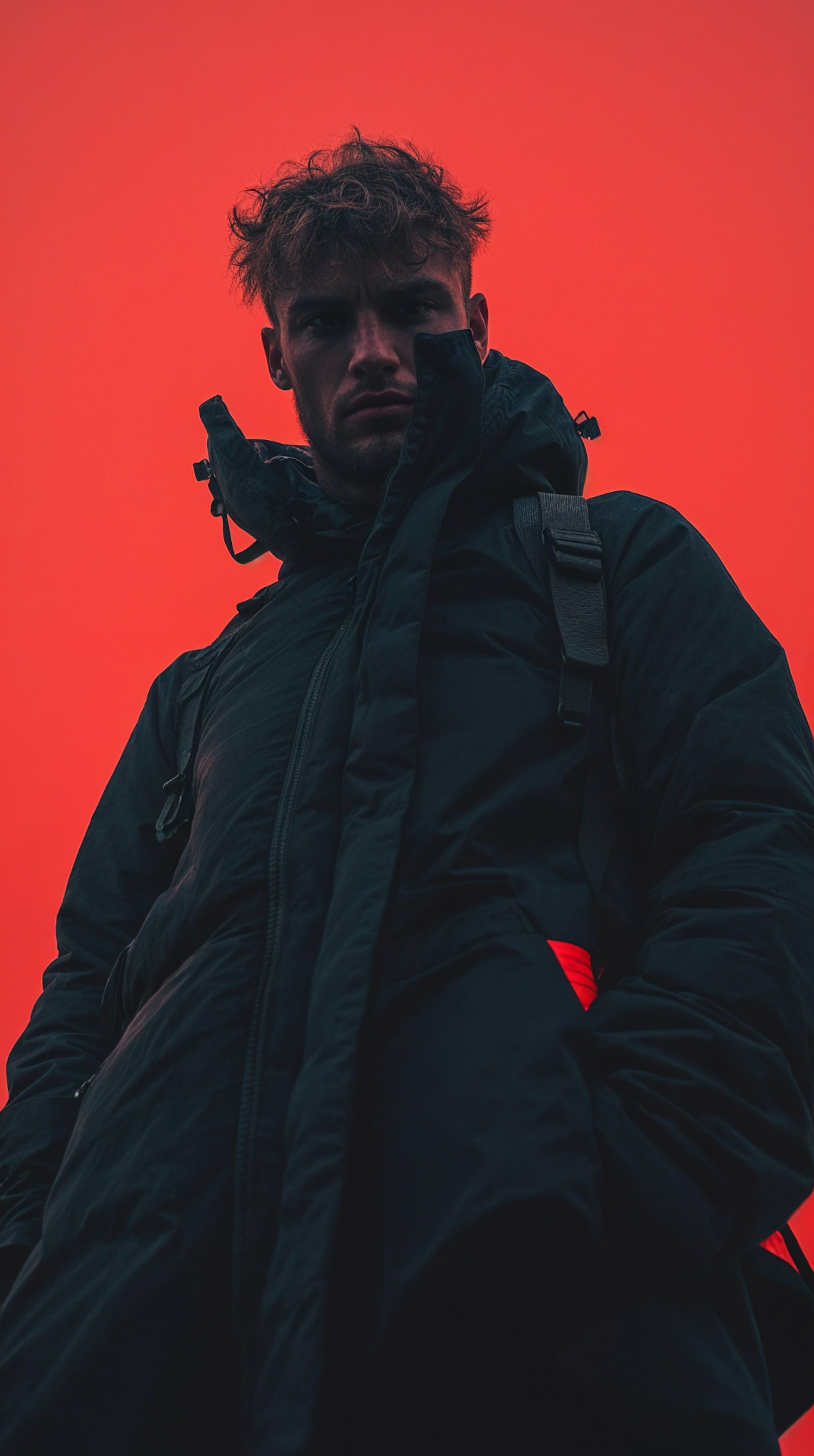 Man in Dark Coat Against Red Background