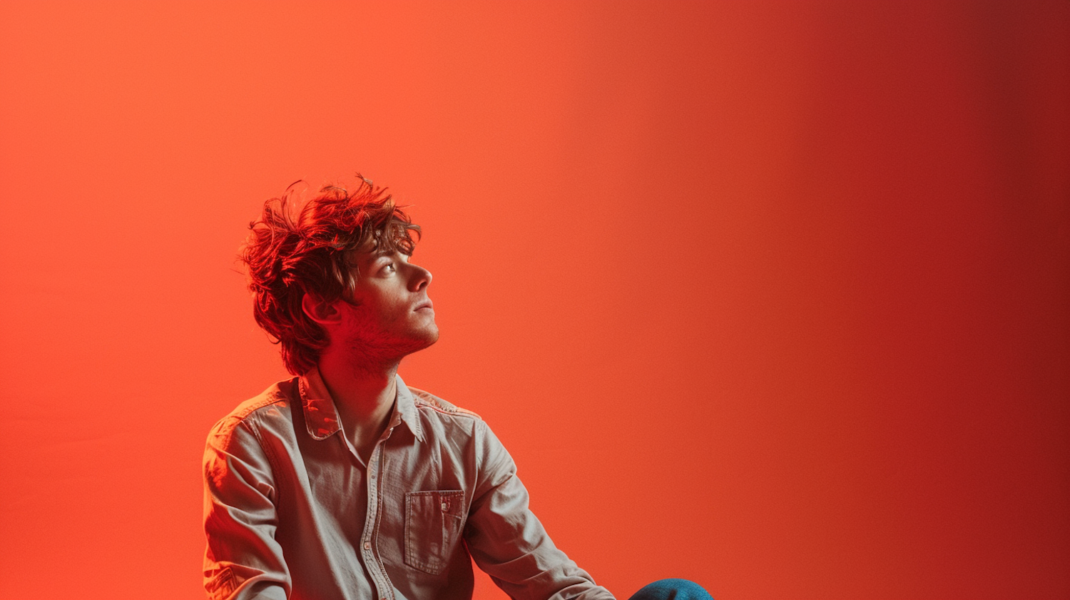 Contemplative Young Man against Vivid Red Background