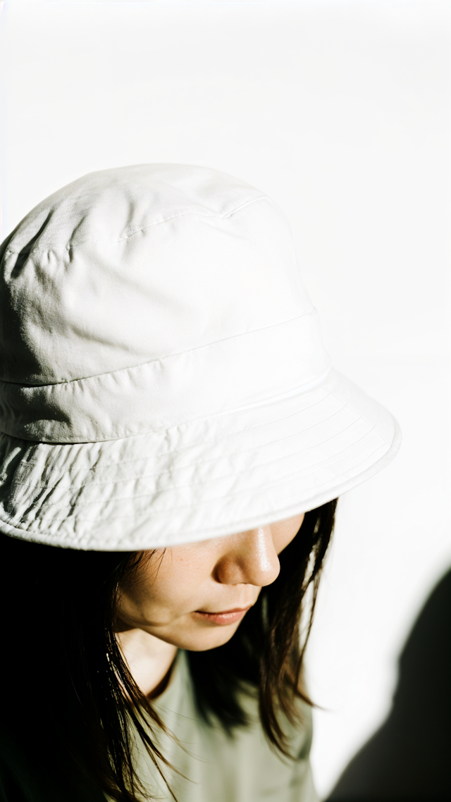 Contemplative Person in White Bucket Hat