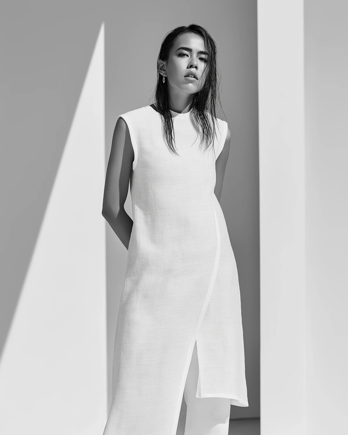 A person in minimalist white attire shot in monochrome with high contrast